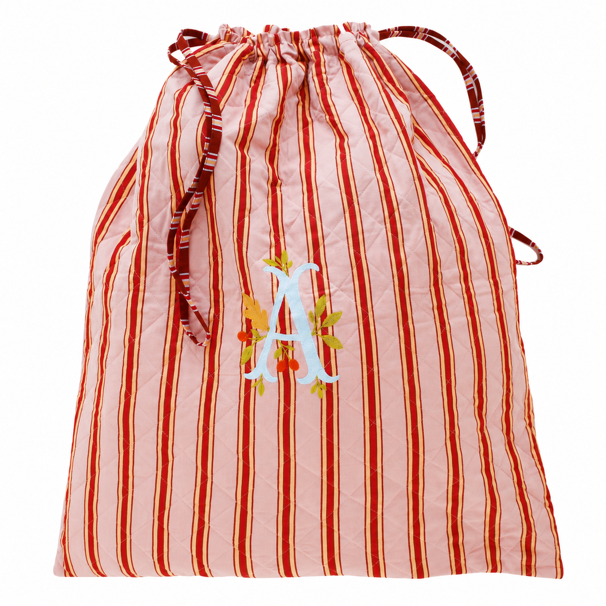 A quilted drawstring bag with vertical red and pink stripes, featuring a white embroidered letter 'A' decorated with orange leaves and gold accents on the front.